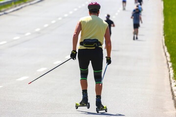 athlete rides roller-skis on the asphalt on the road