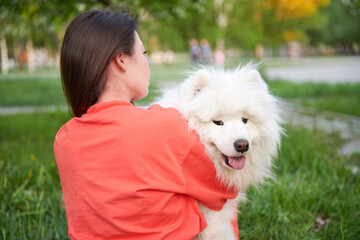 Asian girl wearing orange clothes and white fluffy dog