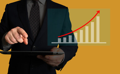 Businessman holding a tablet looking at growing sales volume or stock value increase over the last...