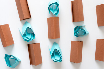 brown paper objects and blue paper rosettes on white