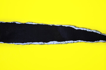 Black torn paper with torn marks on yellow background. top view photo with copy space and text area
