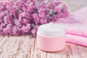 Obraz na płótnie Canvas Natural face skincare product in pink plastic jar with towel on white table.