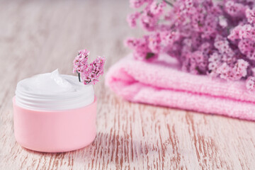 Obraz na płótnie Canvas Natural face skincare product in pink plastic jar with towel on white table.