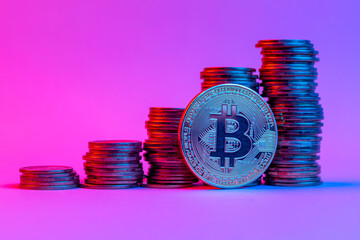 Bitcoin and stacks of coins steps up in neon light