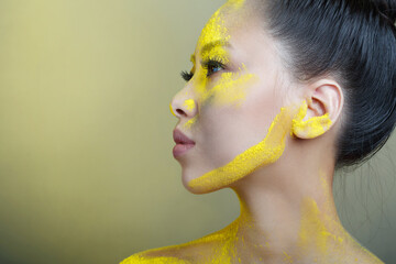 Beautiful asian girl with creative makeup with yellow holi paint.