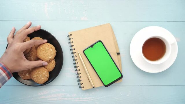 top view of smart phone , cookies and tea on table 