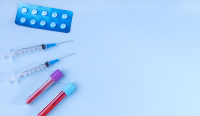 test tubes with blood tests, tablets and syringes with medicines on a blue background. the concept of treatment based on the results of the analysis