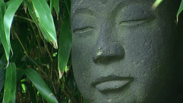 Close-up of statue of Jizo surrounded by bamboo (Bambusoideae)