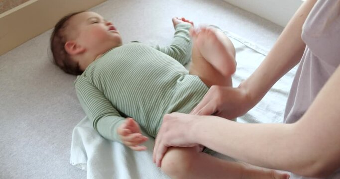 Mom dresses a little boy on the bed. Medicine, healthcare, family, innocence, pediatrics, happiness infant concepts