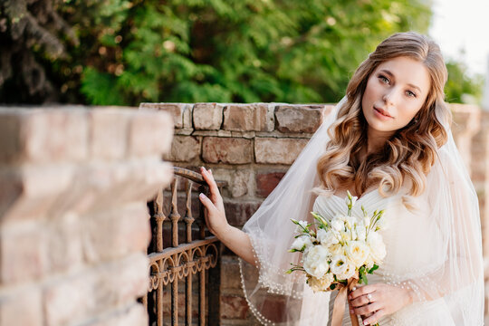 beautiful bride with a bouquet of flowers at the fence.