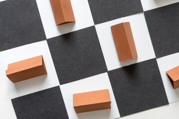 composition with construction paper objects in brown, triangular forms on white and black checkered background
