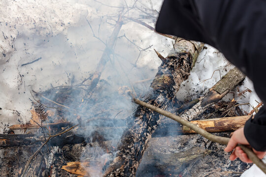 Baton au dessus d'un feu de camp fumant dans la neige