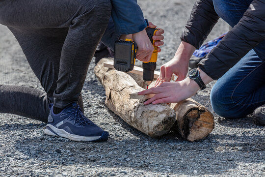 Deux personne faisant un trou dans une buche
