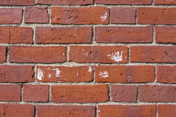 Rows of a brick wall with white paint splatters