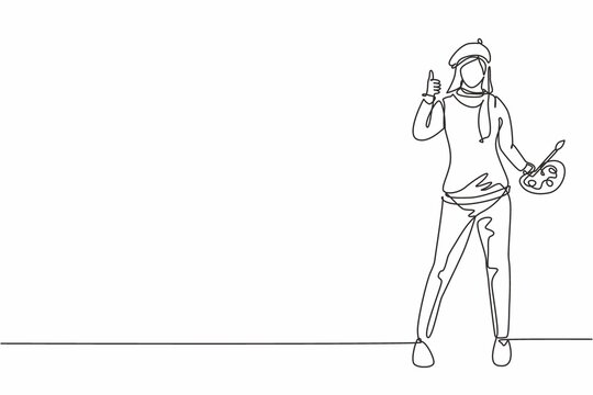 Single continuous line drawing woman painter stands with a thumbs-up gesture using a hat and painting tools to produce artwork in her workshop studio. One line draw graphic design vector illustration