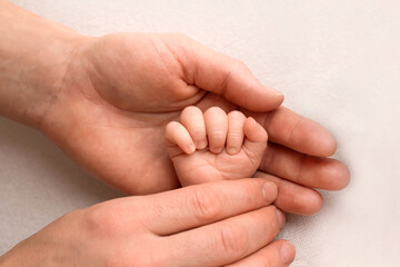 A newborn holds on to mom's, dad's finger. Hands of parents and baby close up. A child trusts and holds her tight