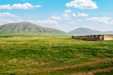 Fototapeta na wymiar Destroyed stockyard and a view of the Chasovnaya and Provalnaya mountains. The picture was taken near the village of Andreevka, Orenburg region