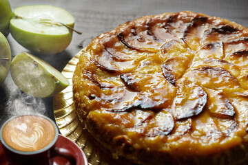 Homemade delicious fresh baked apple tart and cup of hot latte art coffee on rustic wooden table.