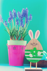 Frühlingsfoto mit einem Hasen und blauen Blumen in einem Topf. Osterfotografie mit Osterkuchen. Kuchen
