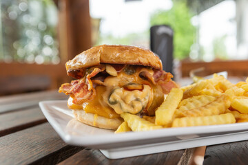 A chilli Cheeseburger with fries on a plate ready to eat at an outdoor dining space in the summer