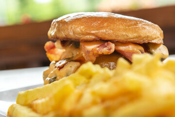 A chilli Cheeseburger with fries on a plate ready to eat at an outdoor dining space in the summer