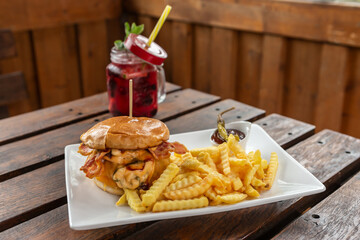 A chilli Cheeseburger with fries on a plate ready to eat at an outdoor dining space in the summer