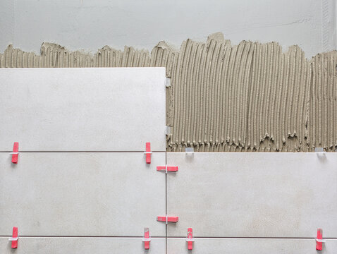 Ceramic wall tile in position over adhesive with lash tile leveling system