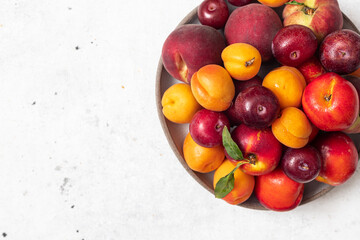 Fresh summer fruits in a plate on a light background