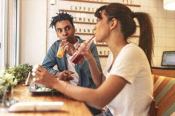 Young couple sitting in street fast food restaurant,eating burgers  and drinks fresh organic juice.