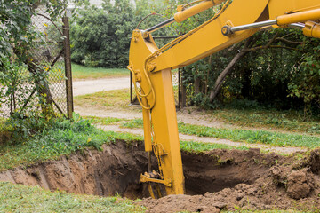The excavator's hydraulic piston digs deep into the pit with a industrial bucket on the...