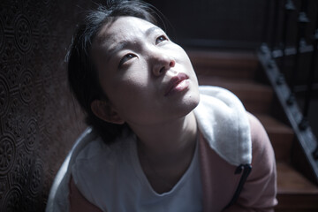 young beautiful Asian woman in pain suffering depression - dramatic indoors portrait on staircase of sad and depressed Japanese girl as victim of bullying and abuse