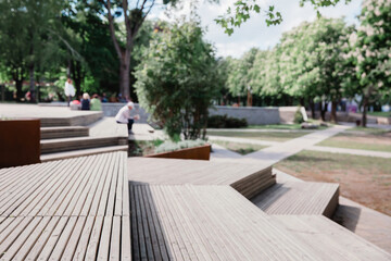 
Modern benches and wooden stairs in city on a sunny day. Public places in city park. Selective focus, blurred background.