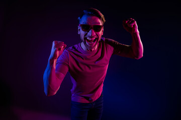 Portrait of attractive cheerful successful funny guy having fun celebrating isolated over dark neon purple color background