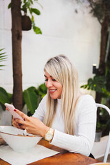 Vertical shot of a blonde Hispanic female using her phone in a restaurant