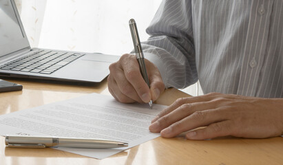 A man sitting signing a contract. Hand of a man writing a document. 