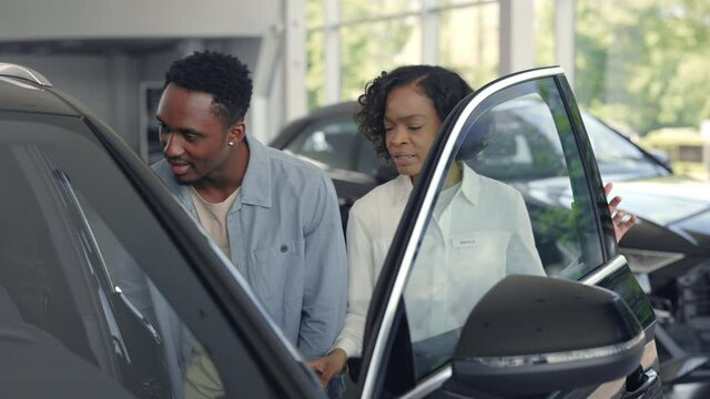 Female dealer presenting luxury car for male customer