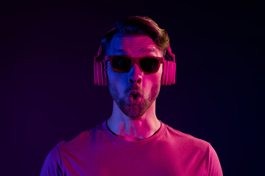 Portrait of attractive amazed funny guy listening bass sound grimacing isolated over dark neon light violet color background