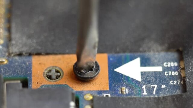 Unscrewing a screw on a laptop motherboard, unscrewing and tightening a bolt into an integrated board