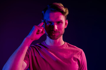 Portrait of attractive serious minded guy touching temple overthinking isolated over dark neon light violet color background
