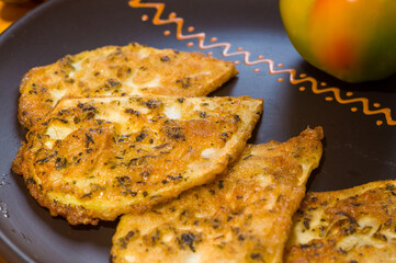 Vegetarian food - celery tuber slices fried in batter in a ceramic plate on a wooden table, close up