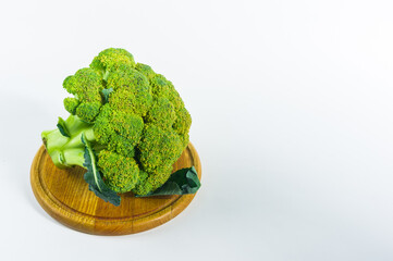 Large raw fresh head of broccoli cabbage on a wooden board, white background, healthy vegetarian food, close-up