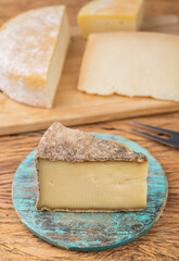 Artisanal Pardinho cheese from Brazil over wooden board with Canastra and Tulha cheese