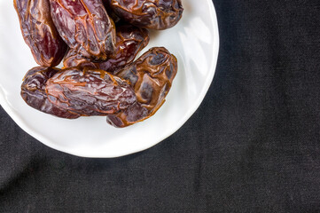 Big luxury dried date fruit in bowls on the dark surface, kurma ramadan kareem concept, close up.