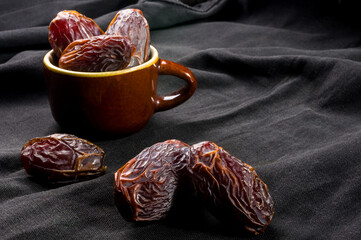 Big luxury dried date fruit in bowls on the dark surface, kurma ramadan kareem concept, close up.