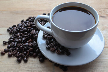 Coffee in cup and coffee beans isolated on wooden background closeup.