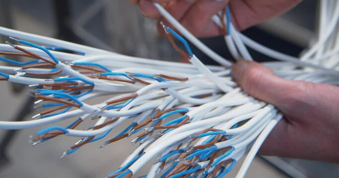 Hands holding and examing a bunch of exposed electric wires, close up 