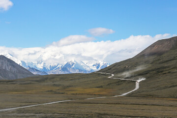 A Bus on a dusty road across grasslands to Mt Denali National Park in Autumn