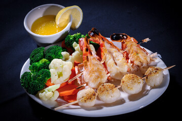 Lobsters and scallops with vegetables dinner, butter and lemon