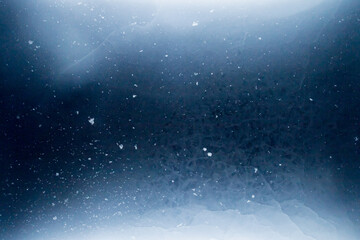 Aerial view of abstract patterns formed by snow and cracks within a blue and white frozen ice sheet