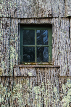 Old window surrounded byunique tree bark siding